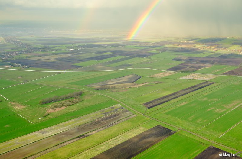 Regenboog over akkers en weilanden